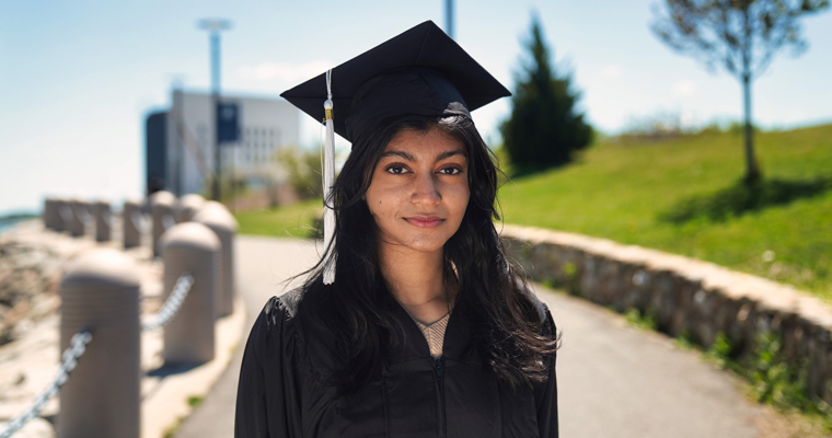 Sheta Roy wears a commencement cap and gown at UMass Boston