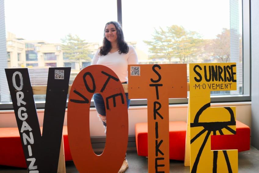 Student stands with VOTE sculpture