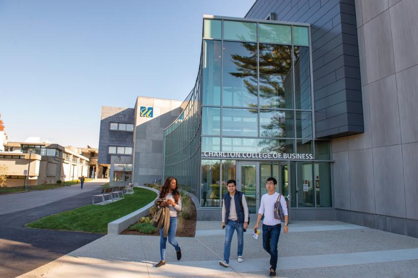 Three students walk out of Charlton College of Business building