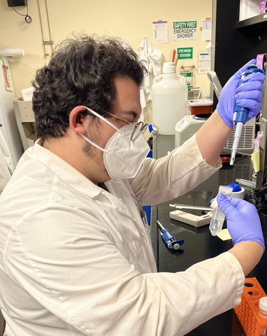 Graduate student Daniel Macveigh-Fierro wears a mask and works in a lab