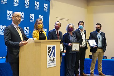 UML Director of Sustainability Ruairi O'Mahony, second from right, and Energy Manager Dan Abrahamson, right, join representatives from UMass Dartmouth, UMass Amherst and Salem State University on stage to accept their Leading by Example award.