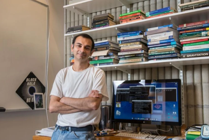 Dr. Gaurav Khanna, Adjunct Professor, and longtime Physics researcher at UMass Dartmouth smiles at the camera while leaning against his office desk