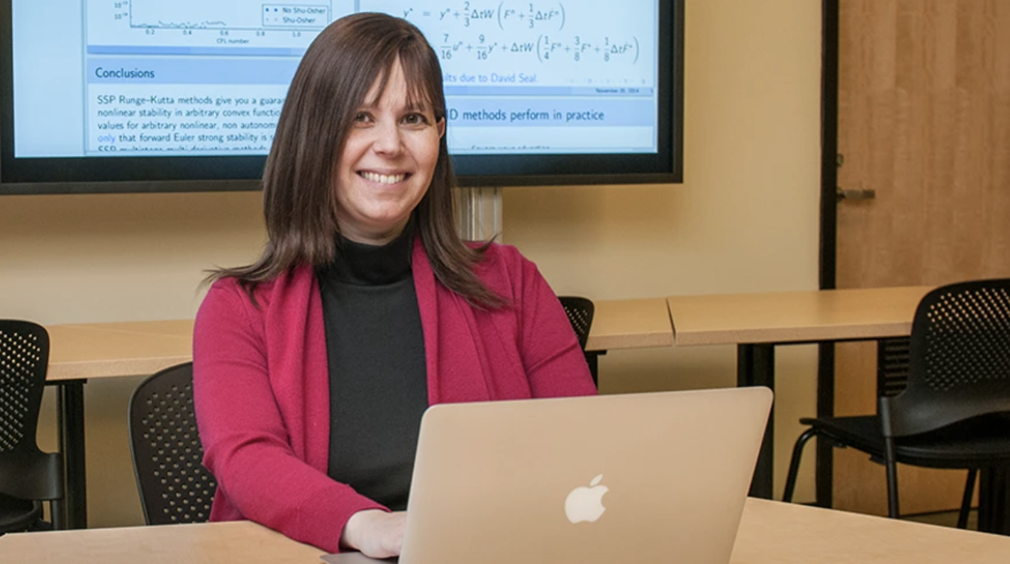 Chancellor Professor of Mathematics Sigal Gottlieb smiles while working on laptop in classroom