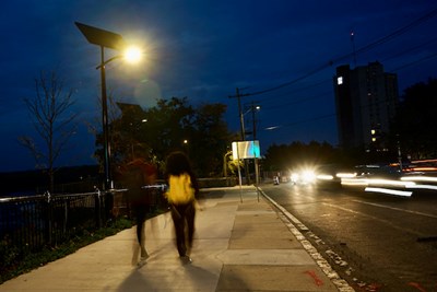 Students walk at dusk under new solar-powered streetlights that the university has installed along the Northern Canal Overlook.