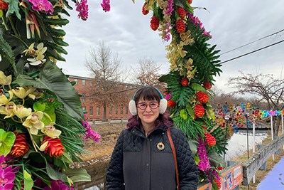 Sociology Assistant Professor Teresa Gonzales standing under an arch of flowers