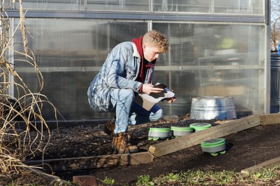 Tertill intern Max Prescott takes notes on the robot's performance on a temporary test bed he built at the Rist Urban Agriculture Farm.