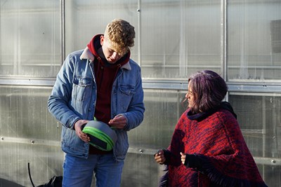 Max Prescott shows a Tertill garden weeding robot to Suzzanne Cromwell, marketing and publicity coordinator for Mill City Grows, an urban farming nonprofit in Lowell.