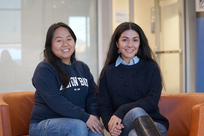 Amy Bui (left) and Eunice Clifton (right) sit on a couch on UMass Lowell campus