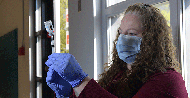 A nurse fills a syringe with a dose of the Pfizer vaccine