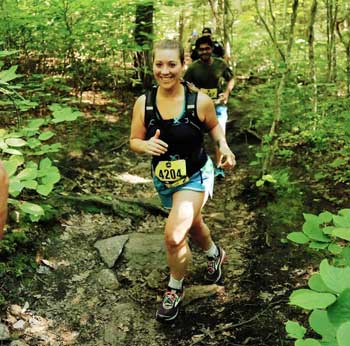 Heather Forchilli runs through woods with a smile on her face